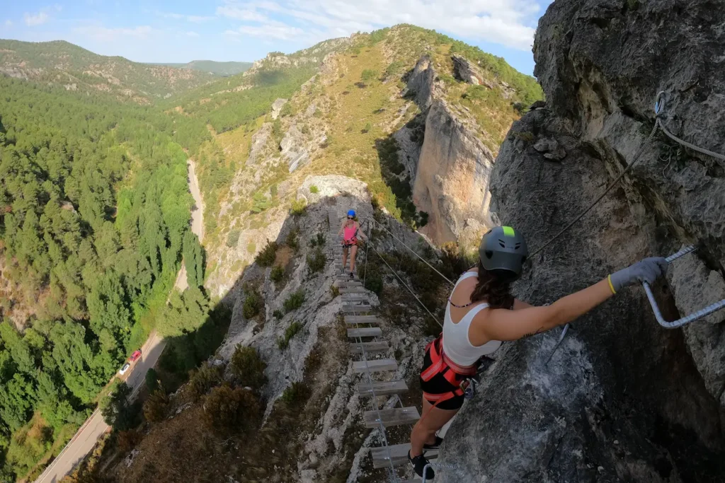 escaladoras siguiendo una pasarela de madera en la via ferrata de priego