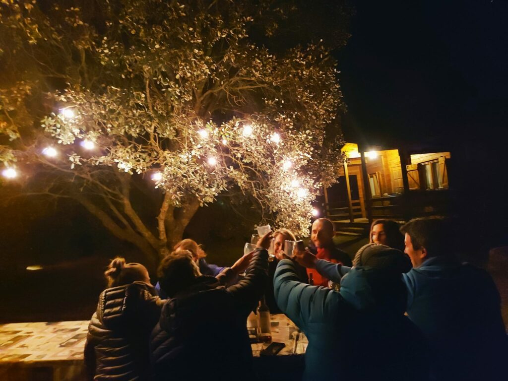 Grupo de amigos de tertulia por la noche en el exterior de las cabañas llano de los conejos